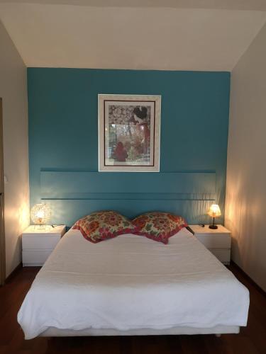 a bedroom with a blue wall and a bed with two lamps at Gîte de la Grée St Jean in La Gacilly