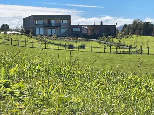 a house on top of a green field with a fence at Cabañas Arrayanes de Huillinco en Chiloé in Chonchi
