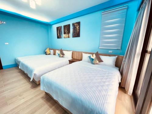 two beds in a room with blue walls at 青翠民宿 in Magong
