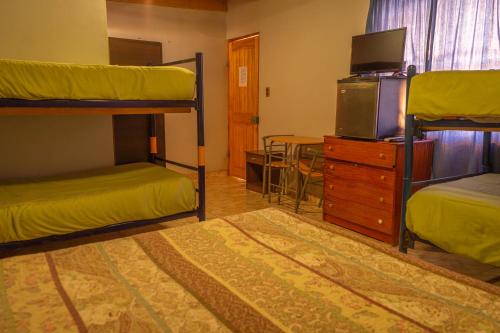 a room with two bunk beds and a tv at La Casa del Sol Naciente in San Pedro de Atacama