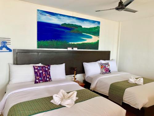 two beds in a room with a painting on the wall at Fisherman's Cottage El Nido in El Nido