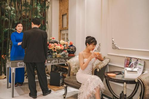 a woman sitting in a chair looking at a man at Mai Hotel in Hanoi