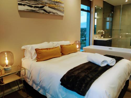 a bedroom with a white bed with pillows and a bathroom at Menlyn Residence - Luxury Six Sleeper in Pretoria