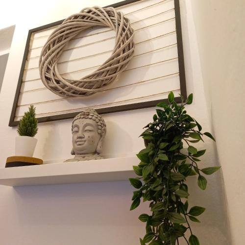 a shelf with a statue and a wreath and a plant at Casa Fiorita 22 Porto Ceresio in Porto Ceresio