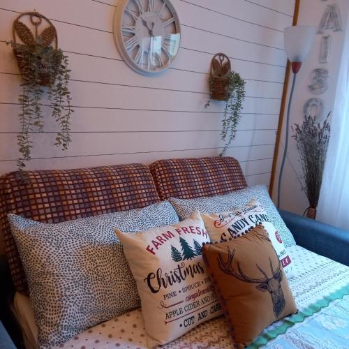 a couch with pillows and a clock on a wall at Casa Fiorita 22 Porto Ceresio in Porto Ceresio