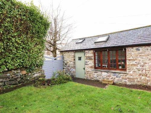 a stone house with a fence and a yard at Little Orchard Barn in St Austell