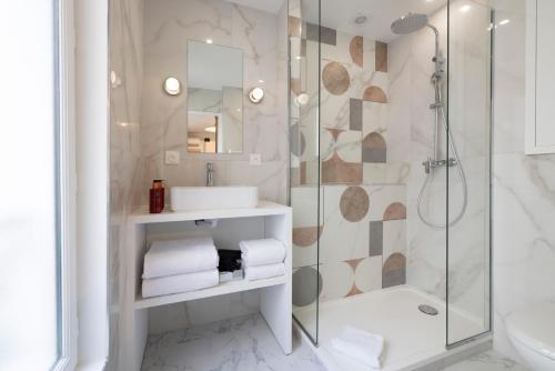 une salle de bain avec douche et lavabo dans l'établissement Yuna Blanche - Serviced Apartments, à Paris