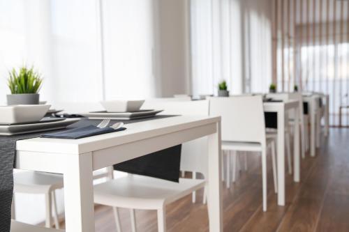 a white dining room with white tables and chairs at Arca Guest House in San Trovaso