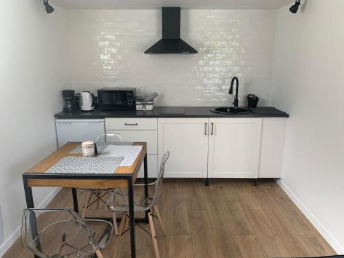 une cuisine avec des armoires blanches et une table avec des chaises dans l'établissement Maisonnette Loft jardin et parking by Art de Voyager, à Étretat