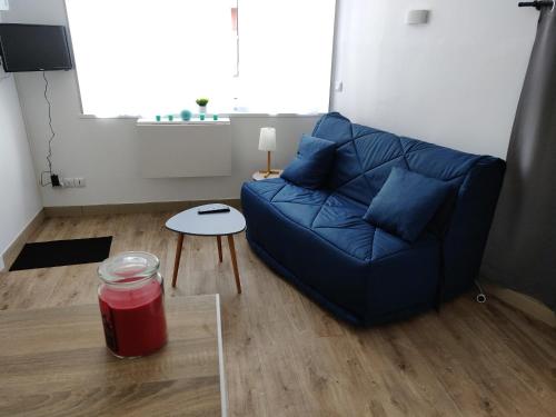 sala de estar con sofá azul y mesa en Studio cosy - proche gare & centre-ville - stationnement - cour intérieure table & chaises, en Saint-Brieuc