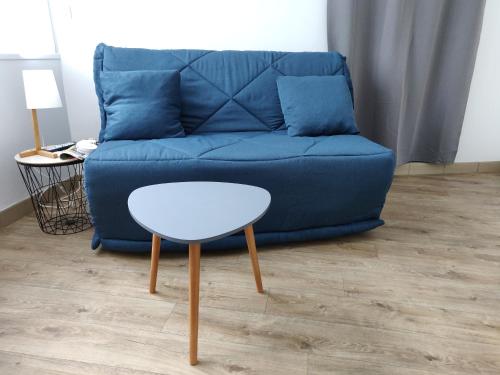un sofá azul con una mesa blanca en la sala de estar en Studio cosy - proche gare & centre-ville - stationnement - cour intérieure table & chaises, en Saint-Brieuc