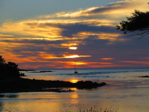 a sunset over the ocean with a sail boat in the water at Dockside Guest Quarters in York