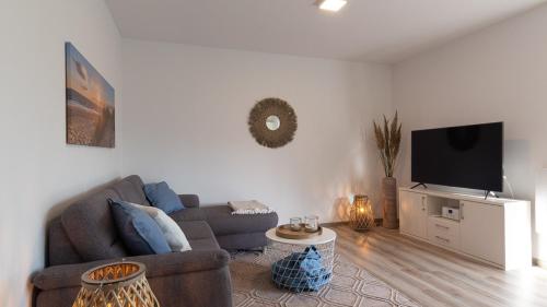 ein Wohnzimmer mit Couch und Flachbildfernseher in der Unterkunft Ferienhaus Sonneneck am Harkebrügger See mit Sauna in Barßel