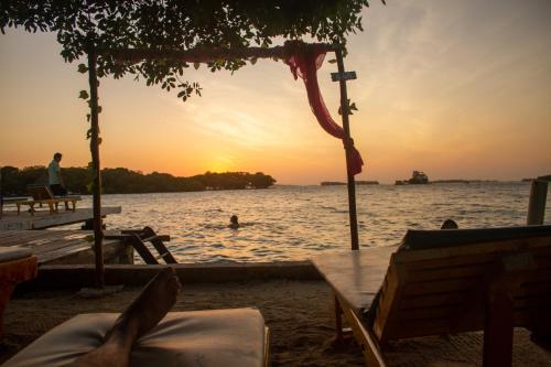 a person laying on the beach watching the sunset at Isla Los Erizos EcoHouse in Isla Grande