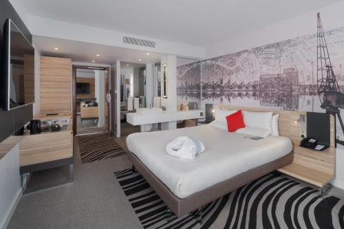 a bedroom with a large bed and a bathroom at Novotel London Excel in London