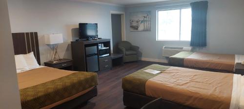 a hotel room with two beds and a television at Rodeway Inn Kalkaska in Kalkaska