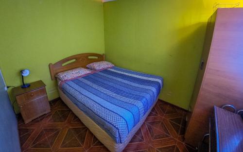 a small bedroom with a bed and green walls at La Casa del Sol Naciente in San Pedro de Atacama