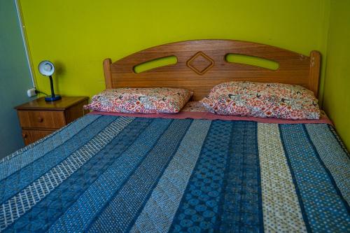 a bed with a wooden headboard and two pillows on it at La Casa del Sol Naciente in San Pedro de Atacama