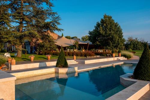 una piscina en un jardín con árboles y un edificio en Chambre d'hôtes Belair, en Muret