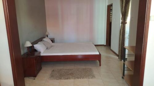 a bedroom with a bed and a table with a lamp at Casa Dona Angela in Mindelo