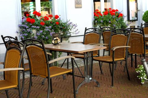 a group of chairs around a wooden table with flowers at Hotel-Restaurant Wanders in Elten