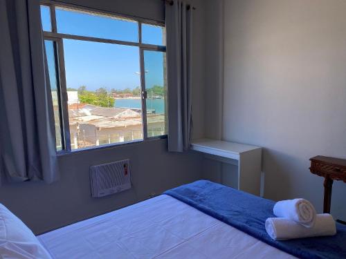 um quarto com uma cama e uma janela com vista em Apto a beira mar no Centro - WIFI 200MB - TV Smart - Cozinha equipada - Portaria 24h - Ar condicionado em Rio das Ostras