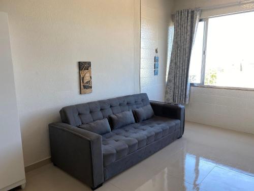 a couch in a living room with a window at Apto beira-mar no centro | ROMM303 in Rio das Ostras
