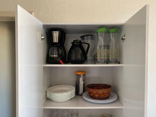 a cupboard with some bottles and plates and dishes at Apto beira-mar no centro | ROMM303 in Rio das Ostras
