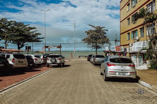 a row of cars parked on a street next to the ocean at Apto beira-mar no centro | ROMM303 in Rio das Ostras