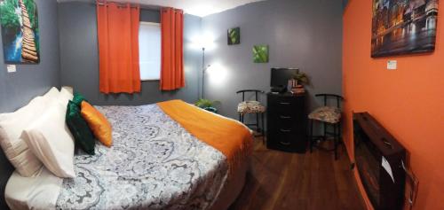 a bedroom with a bed with orange walls and a window at Gracies Fallsview Getaway in Niagara Falls