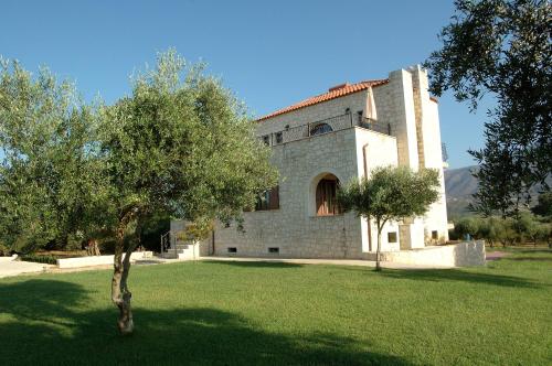 a large brick building with a tree in a yard at Villa Ostria in Georgioupolis