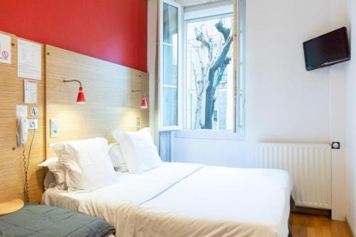 a hotel room with two beds and a window at Hôtel Edmond Rostand in Marseille