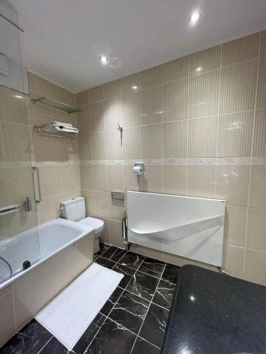 a bathroom with a tub and a toilet and a sink at Résidence des Fleurs in Hombourg-Haut