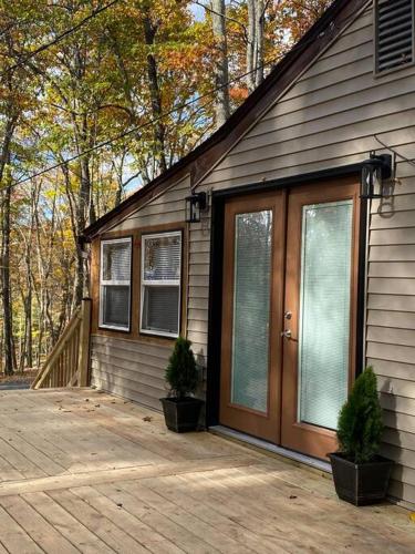 a house with a wooden door and two potted plants at The Nook Lodge - cabin with hot tub at Shawnee and Camelback Mtn in East Stroudsburg