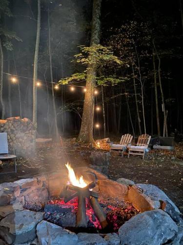 a fire pit in a park at night with two benches at The Nook Lodge - cabin with hot tub at Shawnee and Camelback Mtn in East Stroudsburg