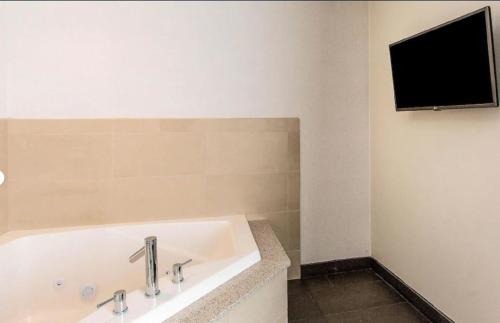 a bathroom with a bath tub with a television on the wall at Wyndham Avon in Avon Center