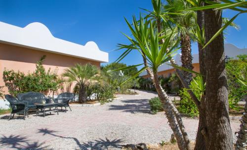 a patio with chairs and palm trees in front of a building at Garden Hotel Ripa in Vieste