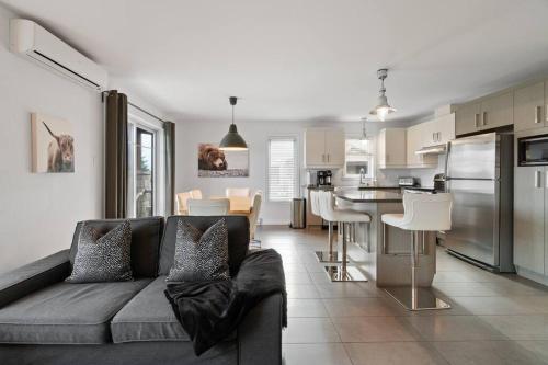 een woonkamer met een bank en een keuken bij INITIAL - GRIZZLY - Mont-Sainte-Anne in Beaupré