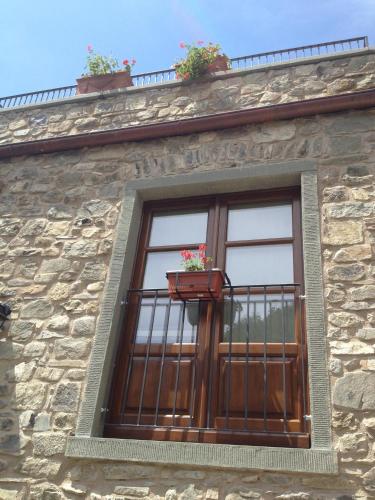 a window on a stone building with potted plants at Agriturismo Montagna Verde Apella in Licciana Nardi