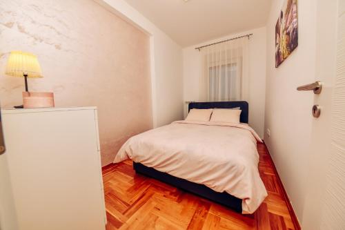 a bedroom with a bed and a lamp on a wooden floor at Apartman A9 Lux in Banja Koviljača