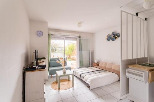ein Schlafzimmer mit einem Bett, einem Sofa und einem Tisch in der Unterkunft Grand T1 bis avec jardin exposé plein sud et salle de sport in Toulouse