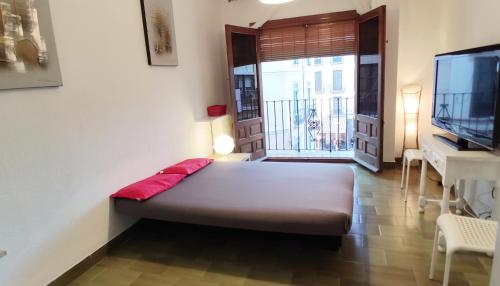 Habitación con cama, TV y mesa. en Apartamento En Centro Historico, en Granada
