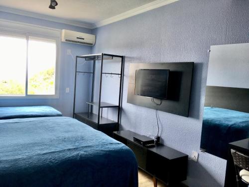 um quarto de hotel com duas camas e uma televisão em Residencial Gralha Azul em Florianópolis