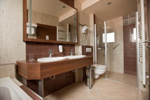 a bathroom with two sinks and a toilet and a shower at Hotel Makar Sport & Wellness in Pécs