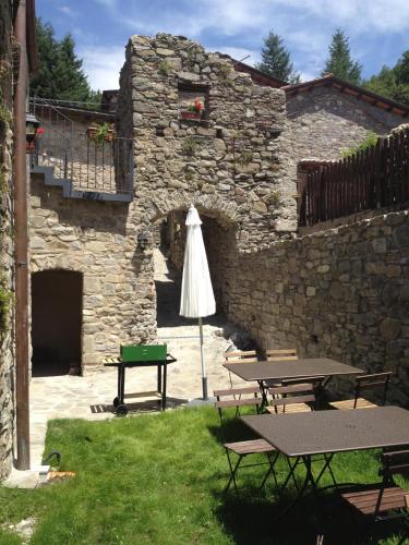 a patio with two picnic tables and an umbrella at Agriturismo Montagna Verde Apella in Licciana Nardi