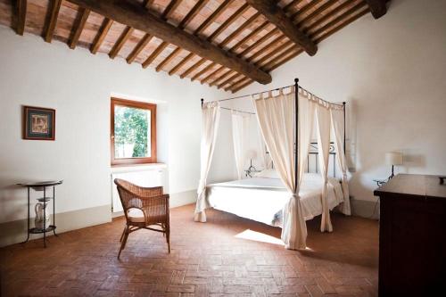 een slaapkamer met een hemelbed en een stoel bij La Spinetta in San Lorenzo Nuovo
