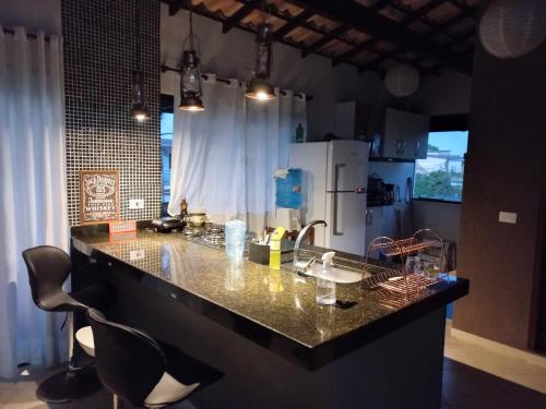 a kitchen with a counter with chairs and a refrigerator at Ilha do Village in Cabo Frio