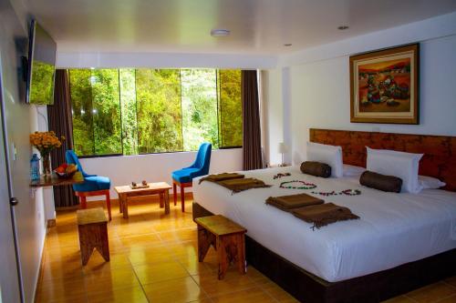 a bedroom with a large bed and a large window at Hotel Tara Machupicchu in Machu Picchu