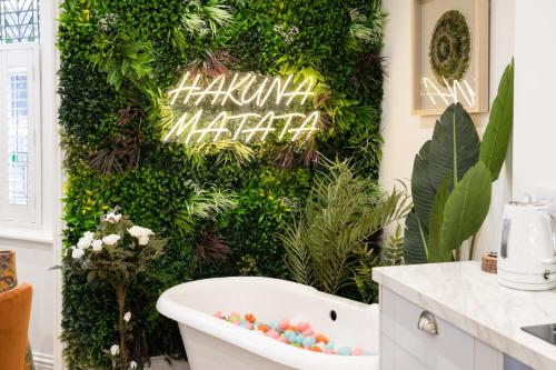 a bathroom with a green wall with a bath tub at The House Of Selfies in Royal Tunbridge Wells