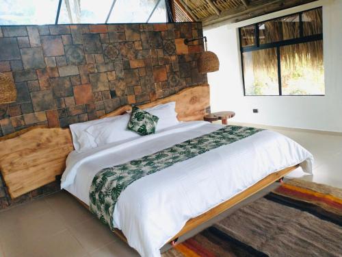 a bedroom with a large bed with a stone wall at Rancho Ecoturistico el Faro in La Mesa